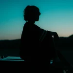 A person reflecting at sunset symbolizes clarity and renewal during Mercury Going Direct in Scorpio.