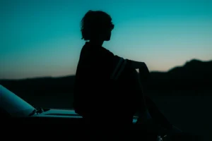 A person reflecting at sunset symbolizes clarity and renewal during Mercury Going Direct in Scorpio.